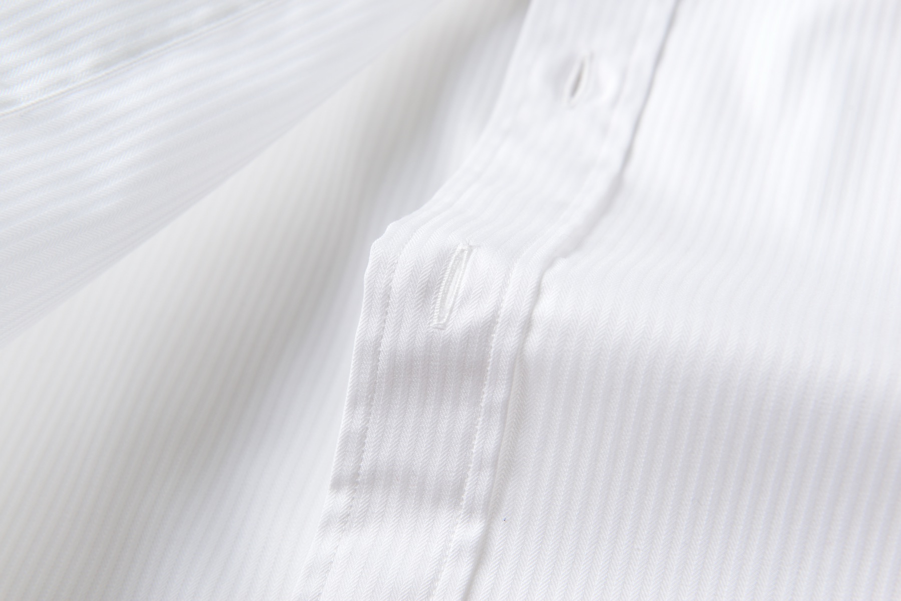 Close-up detail of dress-shirt fabric, button and stitching